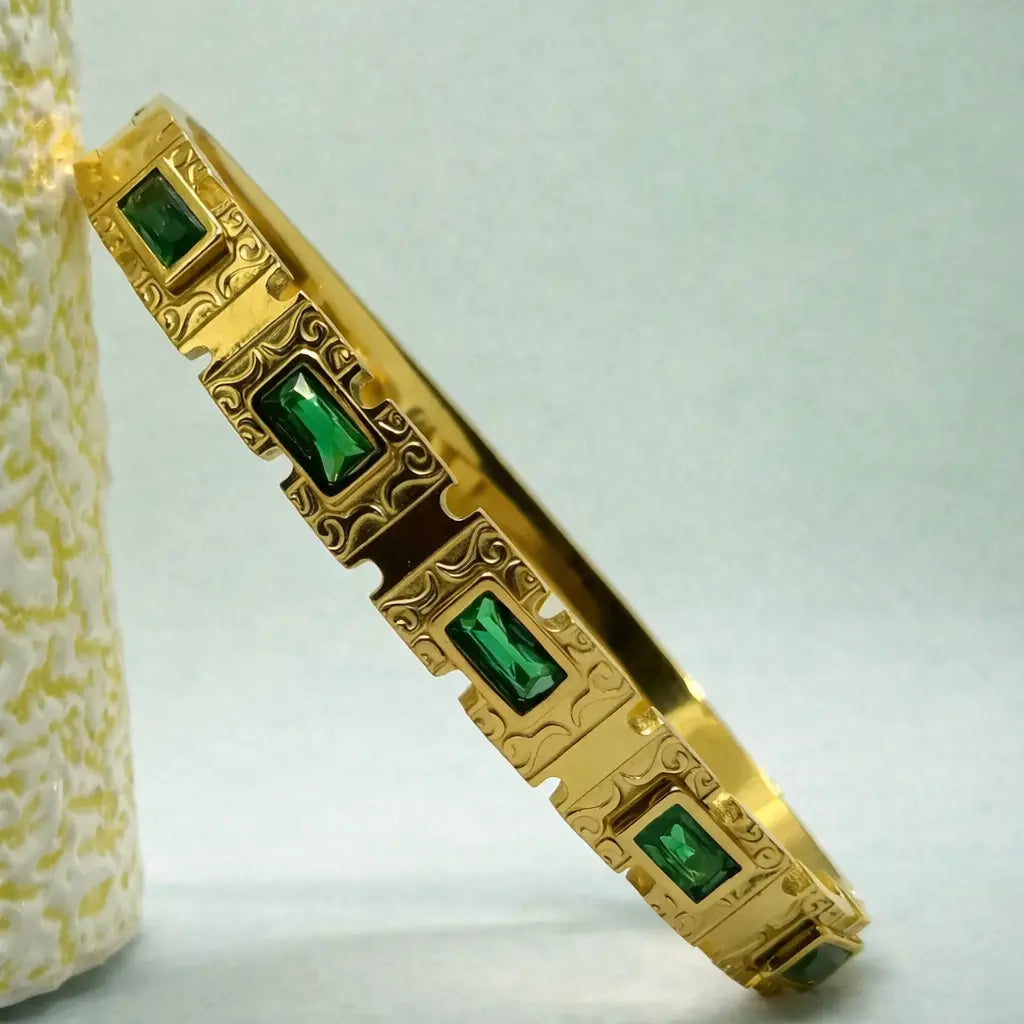 Golden bangle bracelet with emerald cut green stones